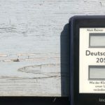 Das eBook Deutschland 2050 vor einer grauen Wand in der Sonne