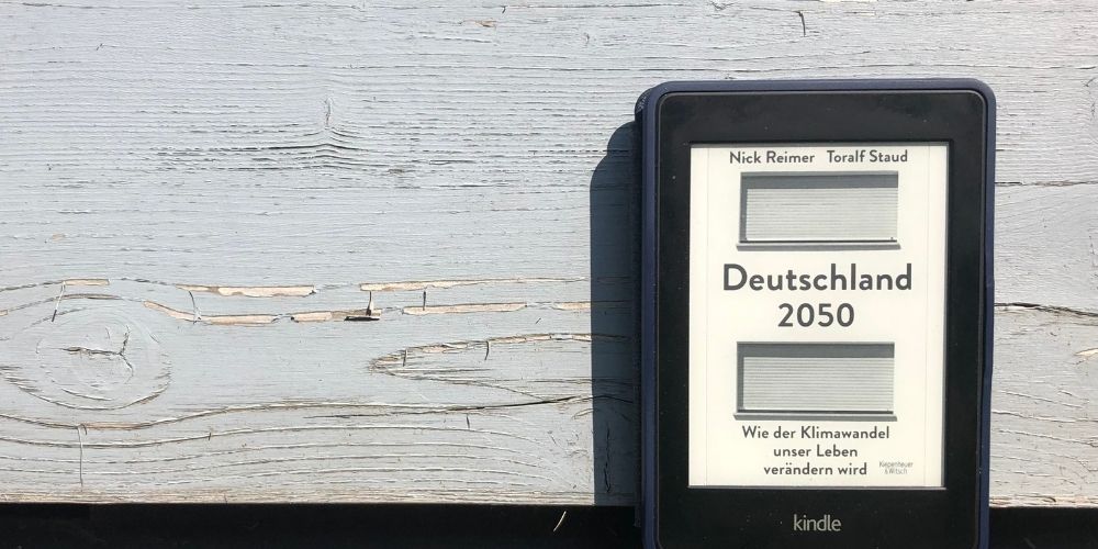 Das eBook Deutschland 2050 vor einer grauen Wand in der Sonne