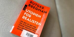 Das Buch "Utopien für Realisten" von Rutger Bregman liegt auf einer grauen Unterlage