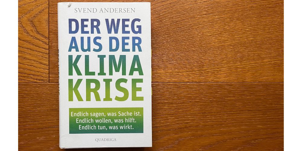 Das Buch "Der Weg aus der Klimakrise" liegt auf einem dunklen Holzboden.