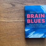 Das Buch Brain Blues (Ängste und Depressionen) liegt auf einem Holzfußboden.